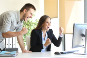 Jubelnde Mitarbeiter vor dem Computer