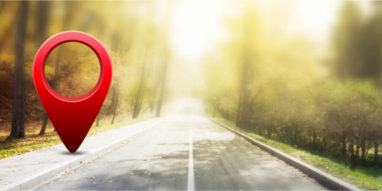 Red GPS pin on asphalt road and beauty autumn nature
