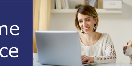 Home-Office - Frau arbeitet am Laptop, während der Hund ihr zusieht
