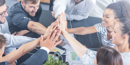 Happy_Gruppe_von_Mitarbeitern_450x300px Ein Gruppe Geschäftsleute arbeiten erfolgreich im Team und zeigen das, durch ein high five nach der Besprechung.